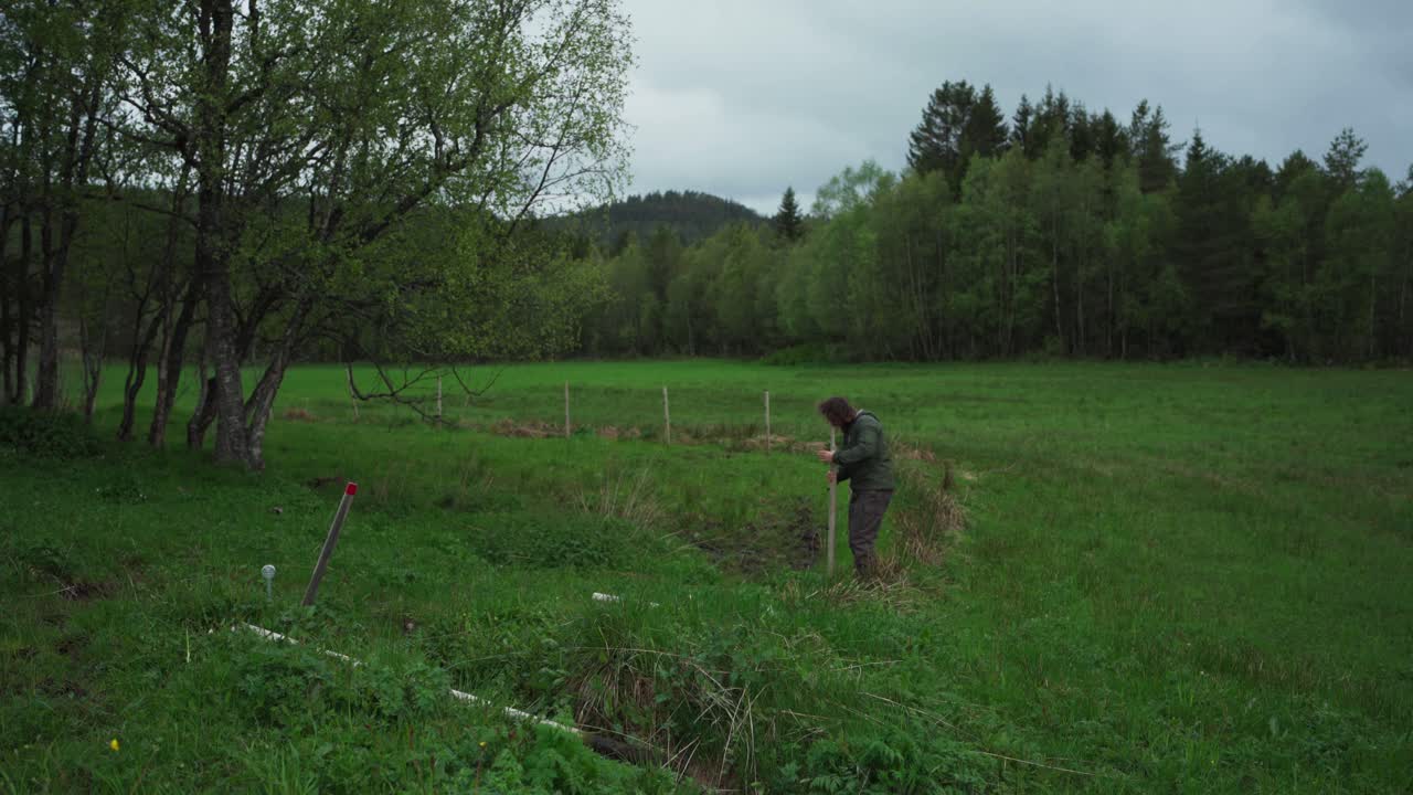 한 사람 이 초록색 농촌 풍경 에서 울타리 기둥 을 제거 한다