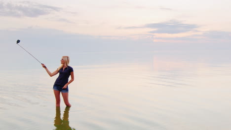 atractiva joven haciendo selfie en un mar tranquilo donde el hermoso cielo se funde con el agua en un