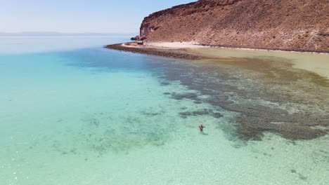 Aerial:-woman-bathing-and-swimming-in-turquoise-sea-shallows,-tropical-seascape,-La-Paz