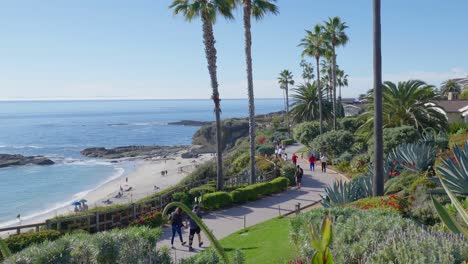 People-walking-along-a-path,-overlooking-a-beach-and-Ocean,-in-Laguna-Beach-California
