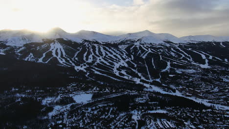 aerial cinematic drone view of breckenridge ski area and town from boreas pass late afternoon sunset over mountain tops mid winter backwards movement pan reveal