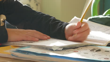 Cerca-De-Una-Chica-Sentada-A-La-Mesa-En-El-Interior-Haciendo-La-Tarea