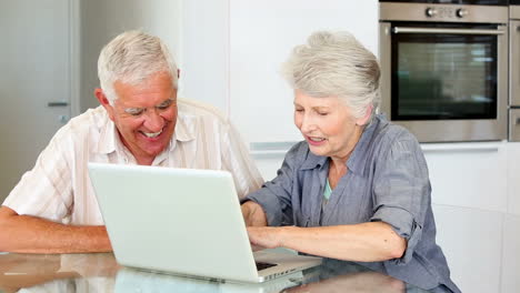 una pareja mayor usando una computadora portátil juntos.