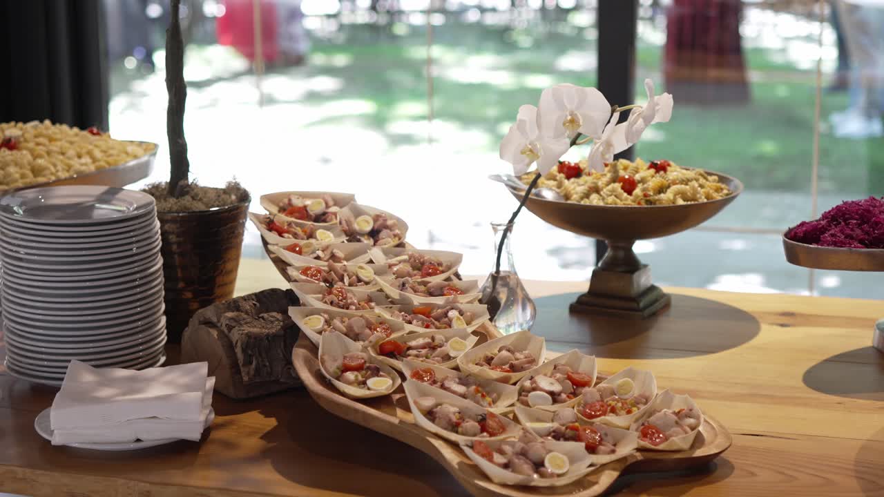 Rustic wedding buffet with gourmet appetizers, pasta, and floral decor on wood