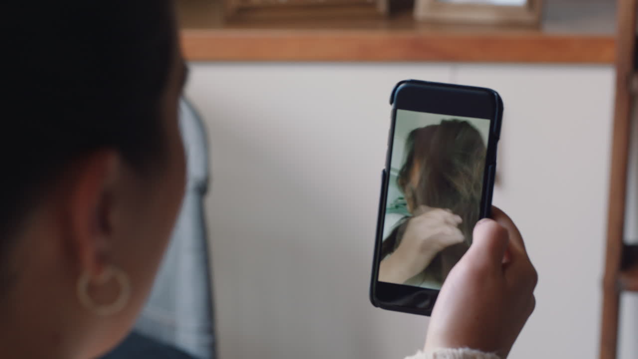 mujer joven teniendo video chat usando teléfono inteligente en casa hablando con un amigo mostrando peinado compartiendo estilo de vida disfrutando de la comunicación en línea