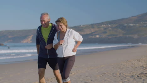 hombre y mujer alegres corriendo a lo largo de la costa del océano en un día de verano