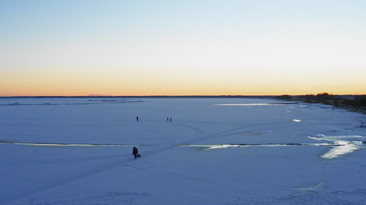 persona arrastra trineo por la nieve durante el amanecer, vista aérea