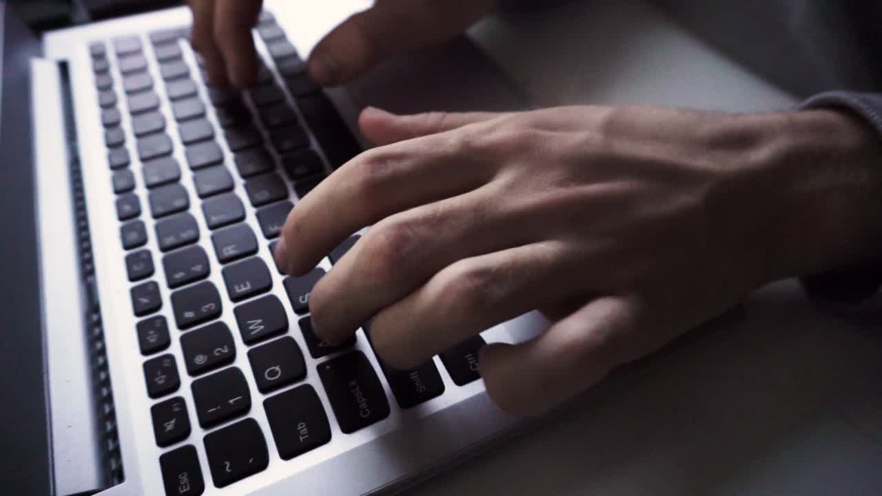 Man typing on laptop keyboard