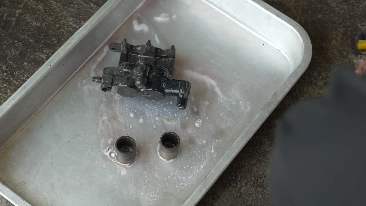 imágenes de primer plano del técnico que trabaja en el proceso de limpieza de la pinza de freno de la motocicleta