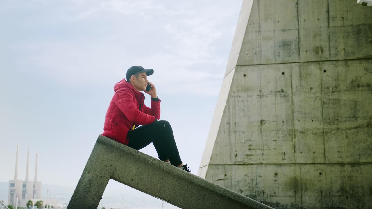 joven atractivo joven de moda que interactúa llamando y enviando mensajes con un teléfono celular en un fondo urbano de la ciudad