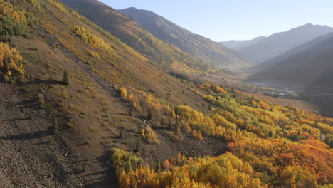 Toma-Aérea-Panorámica-A-La-Derecha-De-Los-Hermosos-Pueblos-De-Montaña-De-Colorado-Y-álamos-Amarillos-Y-Naranjas-Brillantes-Durante-El-Otoño-En-Las-Montañas-De-San-Juan-A-Lo-Largo-Del-Viaje-Por-Carretera-De-Un-Millón-De-Dólares