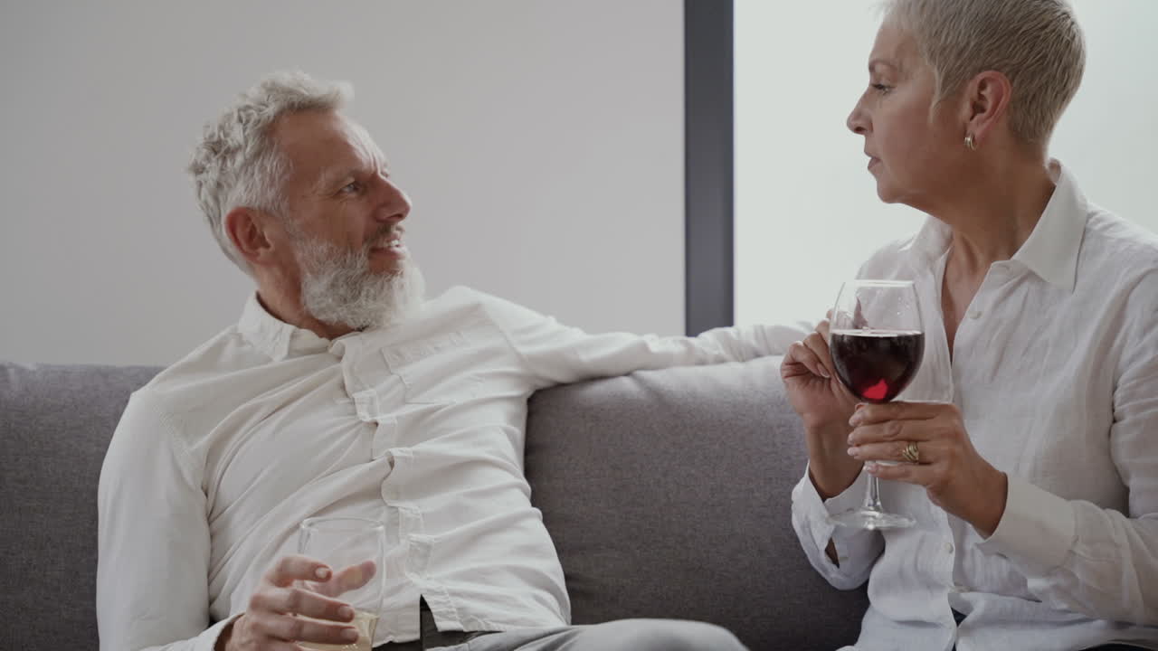 웃으면 서 와인 한 잔을 마시는 소파에 앉아 여자와 남자 행복 수석 친구 1