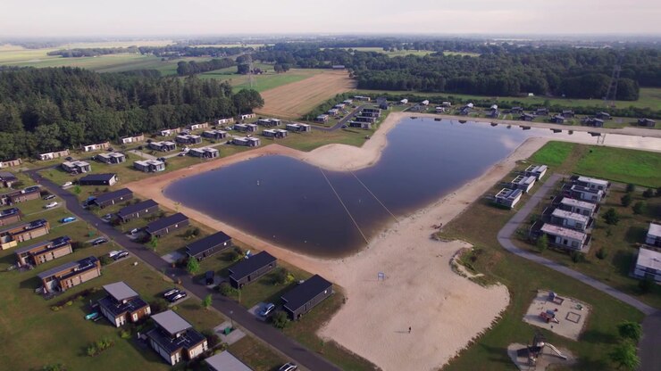 Aerial of recreational Hoge Hexel bungalow park with summer homes around a pond with beach side access