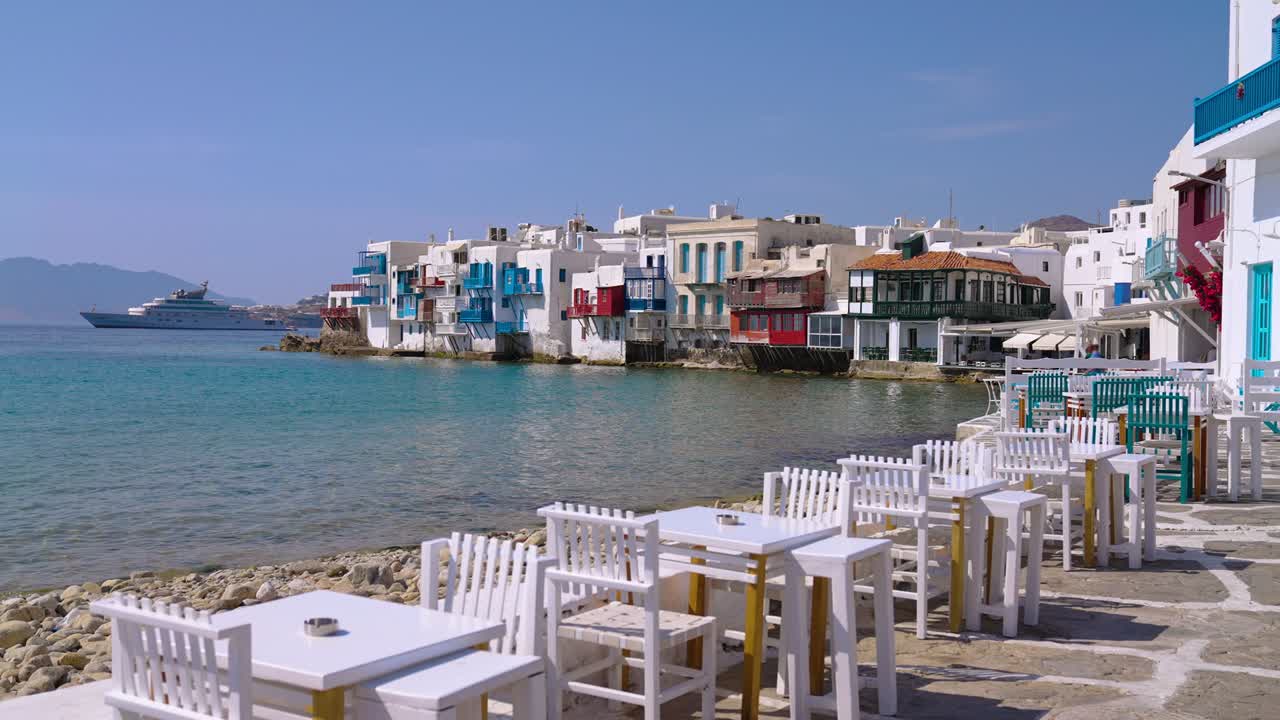 tablas y sillas de un pintoresco restaurante frente al mar en little venice, mykonos, grecia