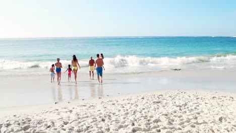 three smiling generation family running to the sea