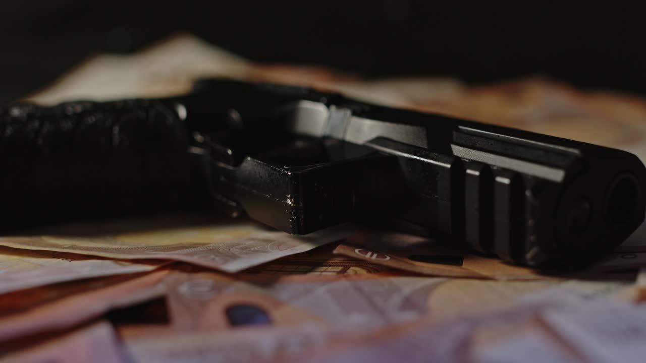 cerrar el muñeco de una pistola en una pila de dinero con sirenas parpadeantes en el fondo