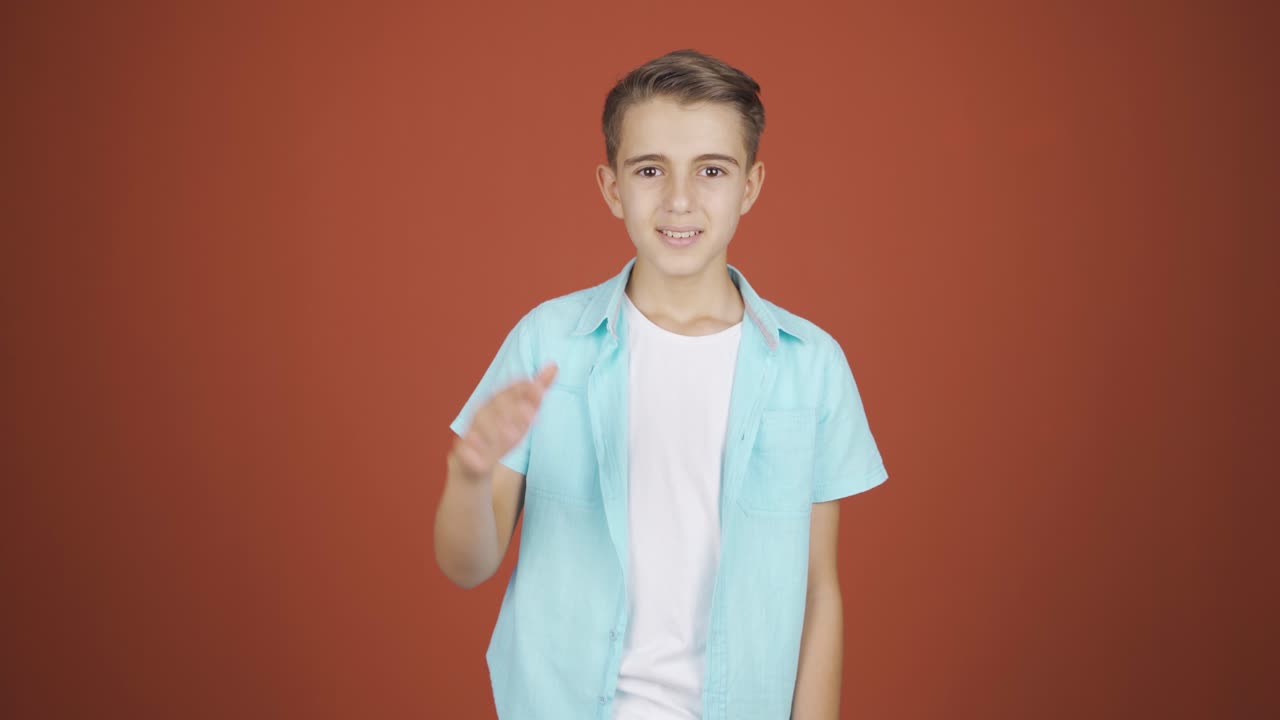 un chico feliz saludando a la cámara.