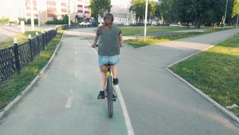 side view of a girl cycling on a road with flowers in a basket and exploring the city, slow mo, steadicam shot