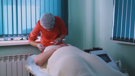 beautician in mask and cap works with plus-size woman face