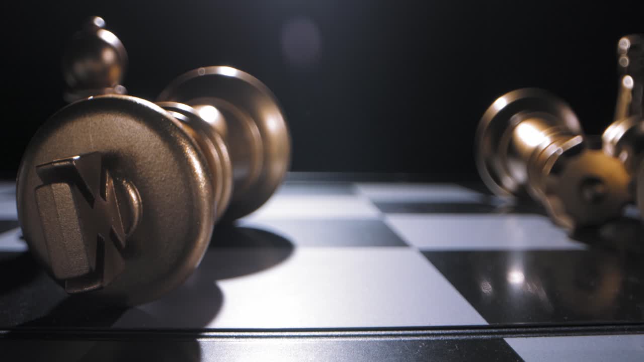Defeated gold king chess piece rolls to a stop on chess board