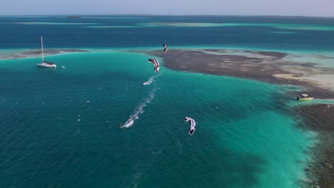 three people on kite boards showing their abilities in beautiful ocean water