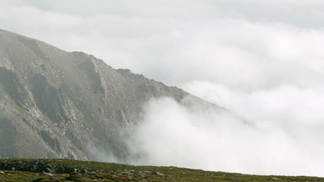 beautiful thick clouds moving by the mountain peaks at serra da estrela in portugal - close up