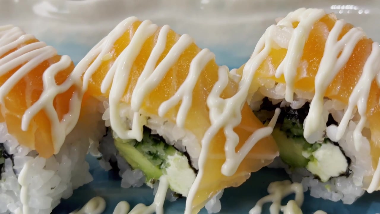 Lähikuva California roll -sushista aseteltuna tarjoilulautaselle, sisältäen riisiä, mereneläviä, avokadoa ja tuoreita ainesosia elegantilla esillepanolla