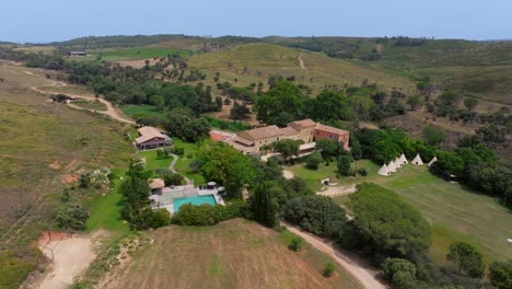 aerial establishing shot of a rural villa with sports facilities and small tents