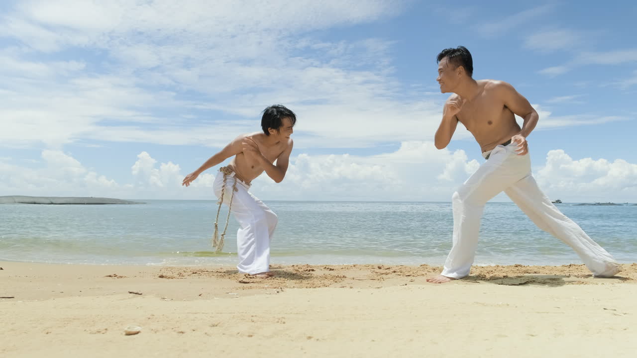dos hombres bailando capoeira en la playa