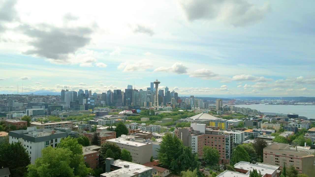 Vista aérea de drone aproximando-se do horizonte do centro de Seattle, apresentando a Space Needle, arranha-céus modernos e a Baía de Elliott durante o dia em Seattle, Washington, EUA