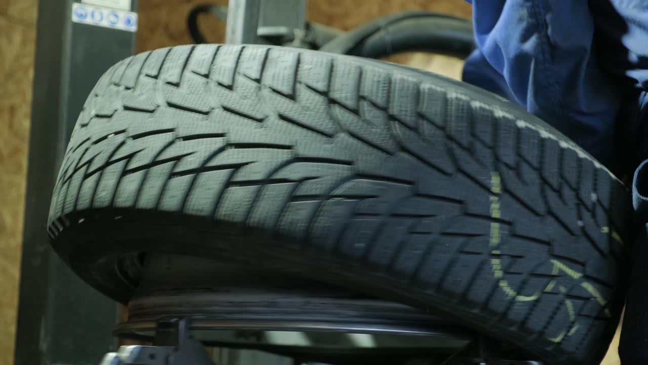 cambiar un neumático, un mecánico de automóviles está cambiando un neumático en un garaje