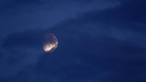 night view of the moon covered by flowing dark clouds