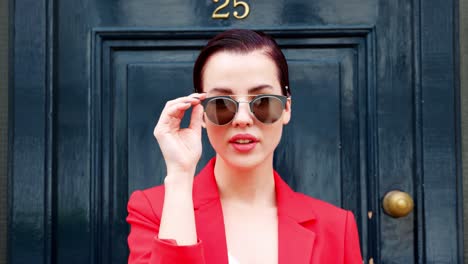 Stylische-Frau-Mit-Sonnenbrille,-Die-Vor-Der-Blauen-Tür-Steht-Standing