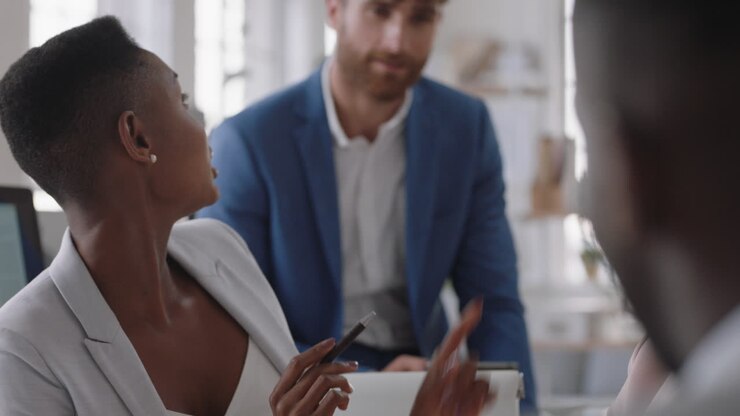 donna d'affari afroamericana che chiacchiera con i colleghi in ufficio, si incontra, parla, condivide idee nel posto di lavoro aziendale