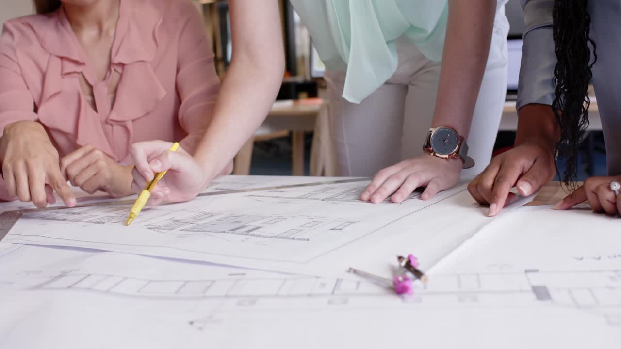 sección media de diversas arquitectas discutiendo planos en el escritorio de la oficina, en cámara lenta.