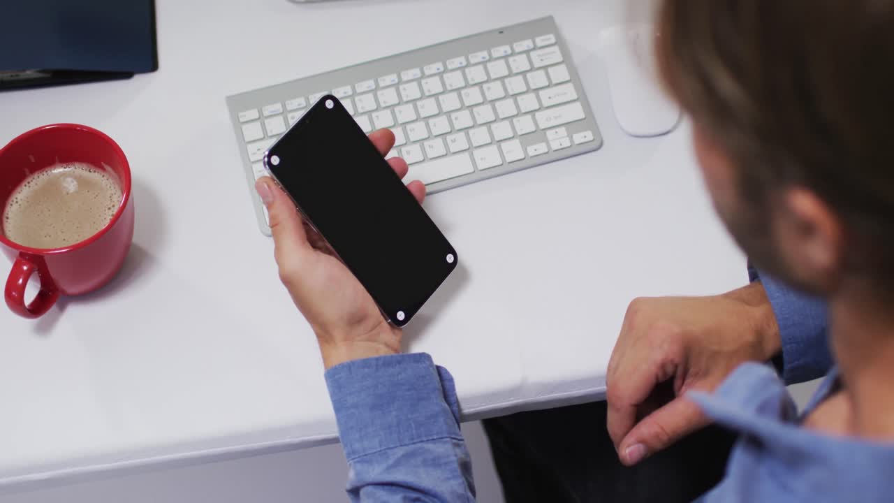 hombre de negocios caucásico haciendo una videollamada usando un teléfono inteligente en el escritorio de la oficina