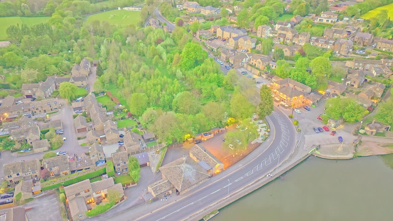 Crane up drone shot of road next to Newmillerdam Country Park lake during the day in Newmillerdam, suburb of Wakefield, West Yorkshire, England