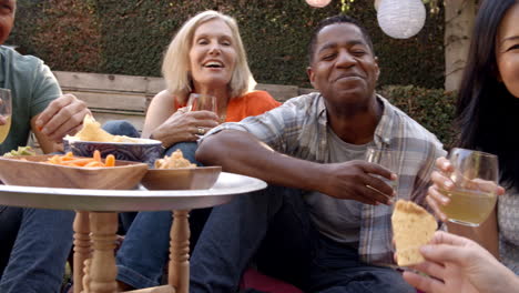 Group-Of-Mature-Friends-Enjoying-Picnic-In-Backyard-Together