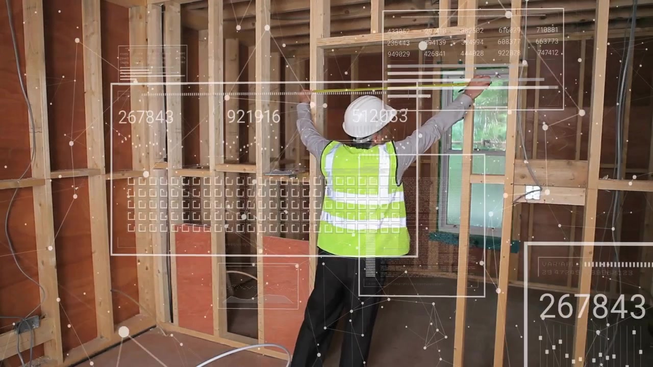 Builder lifting right arm and activating AR grid with floating data while measuring wall dimensions