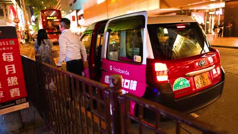 un taxi recoge pasajeros en una concurrida calle de hong kong.