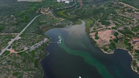 Filmische-Drohnen-Enthüllung-Der-Insel-Menorca-In-Spanien-Mit-Segelyachten,-Die-Unten-Im-Hafen-Festgemacht-Haben