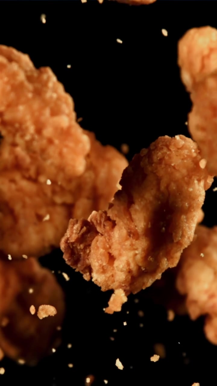 Nuggets di pollo fritti dorati e croccanti che galleggiano al rallentatore