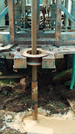 digging a hole in ground with rig machine. water drilling equipment. vertical video.