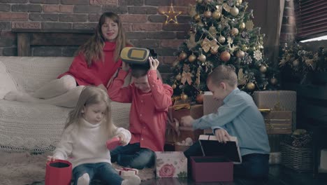 small children open christmas present boxes woman watches