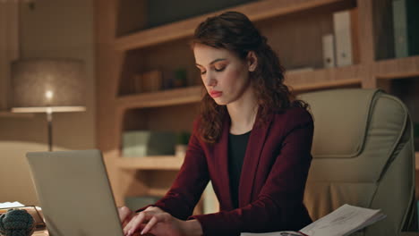 focused businesswoman typing laptop at dark workplace close up. serious woman