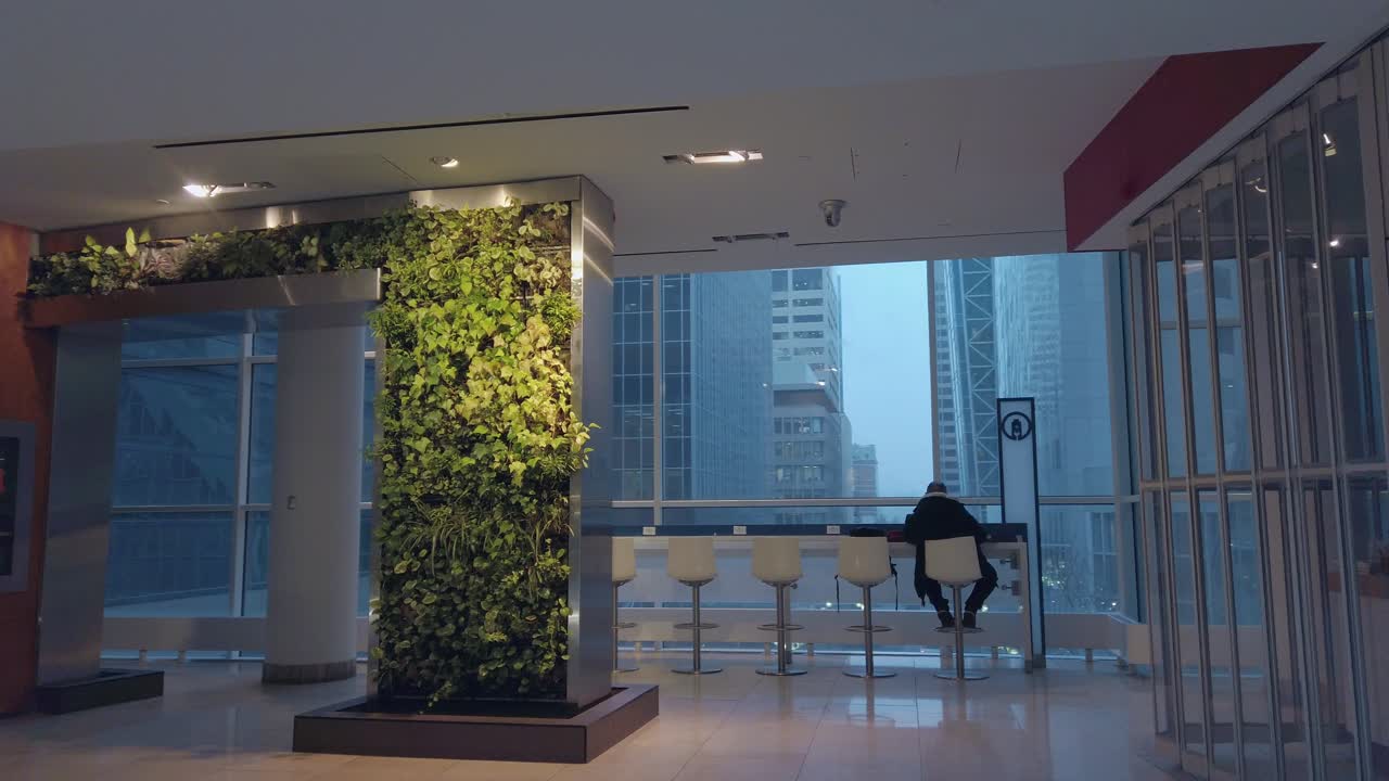 hombre sentado junto a una gran ventana en el centro comercial viendo rascacielos callejeros de la ciudad centro de calgary invierno camiones