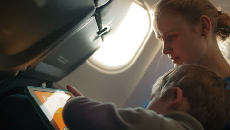 mother and son with touchpad in the plane