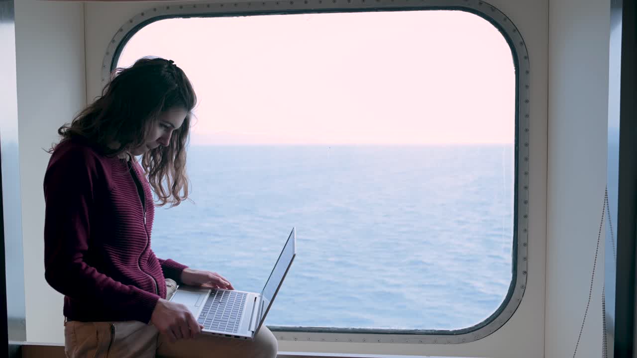mujer sonriente navegando por computadora portátil en un crucero