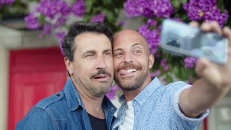 happy gay couple taking selfie in street and making grimaces