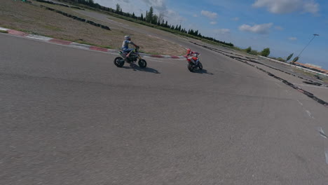 action fpv drone pov following motorcycle riders turning through racetrack corners, aerial view